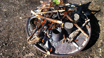 konservburkar med olika innehåll står i en eld på en eldplåt.. Fotograf: Anna Aldén 
